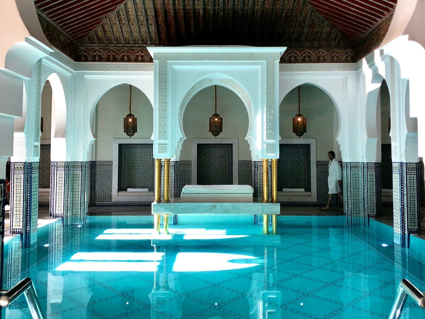 Piscine intérieure carrelée de bleu sous une verrière