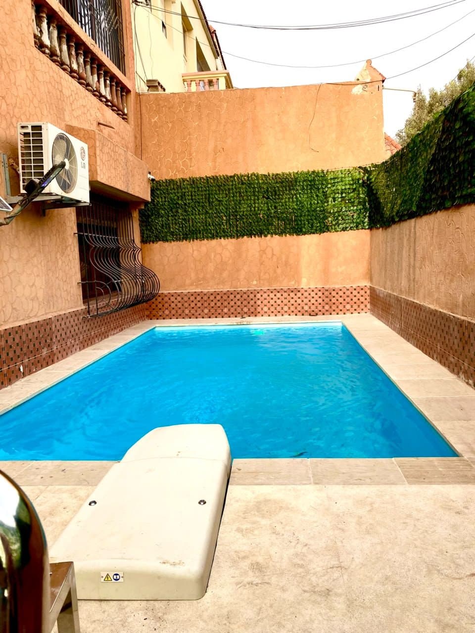 Piscine de patio entre murs ocre et haie végétale, réalisation RiverPool